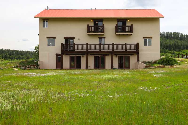 Back of the lodge with two private balconies, the long deck and lower-level doors to the meadow