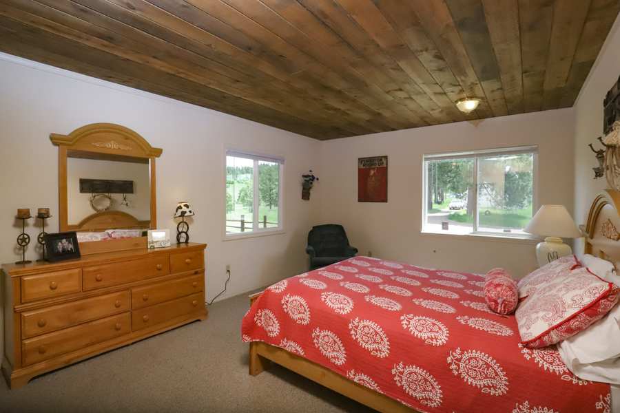 Main-floor queen bedroom with two windows onto the pines