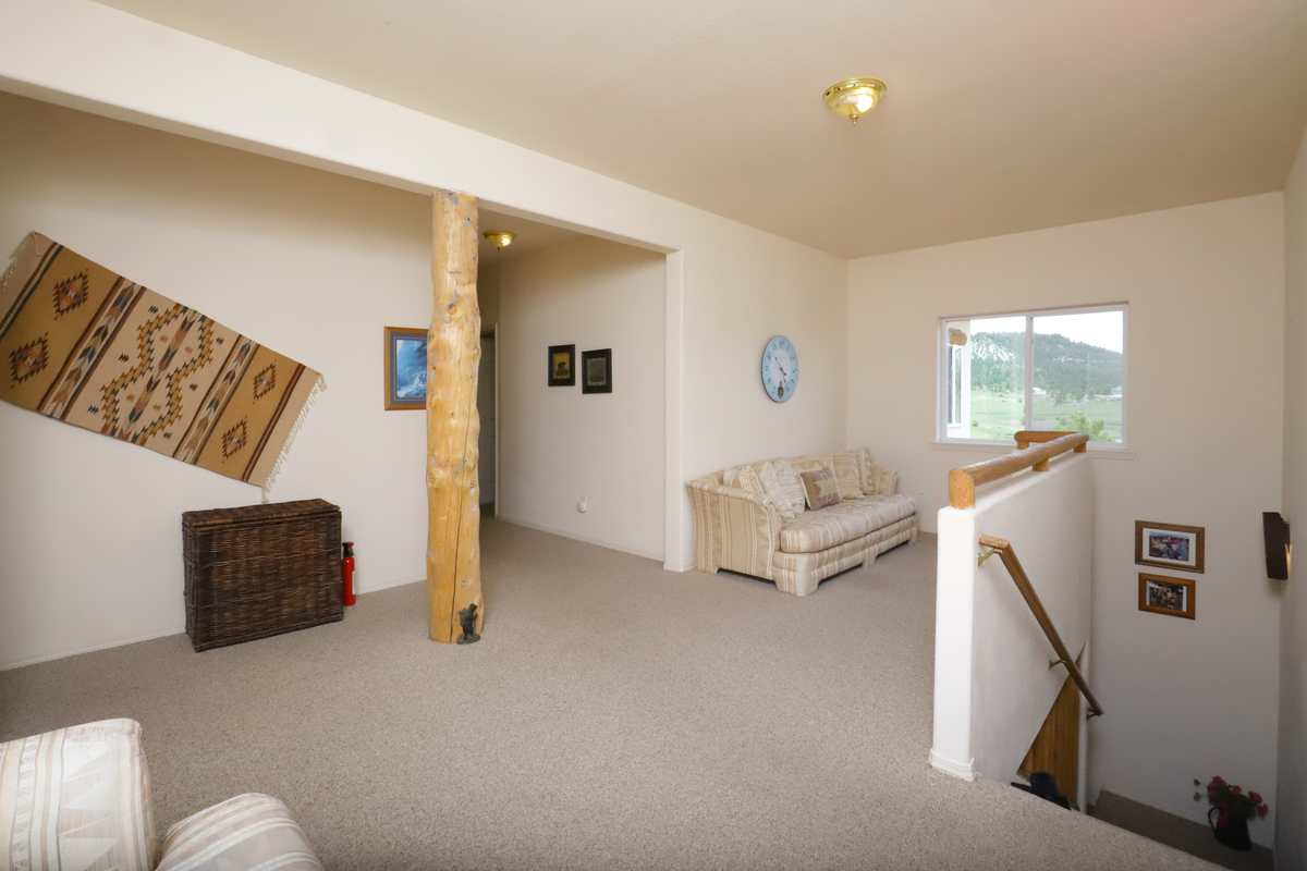 Upper-floor landing with a sitting area, log post and window onto the hills
