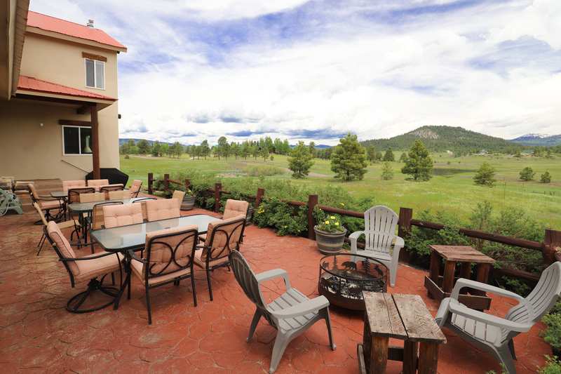 Back patio with dining tables, Adirondack chairs and fire pit overlooking the valley