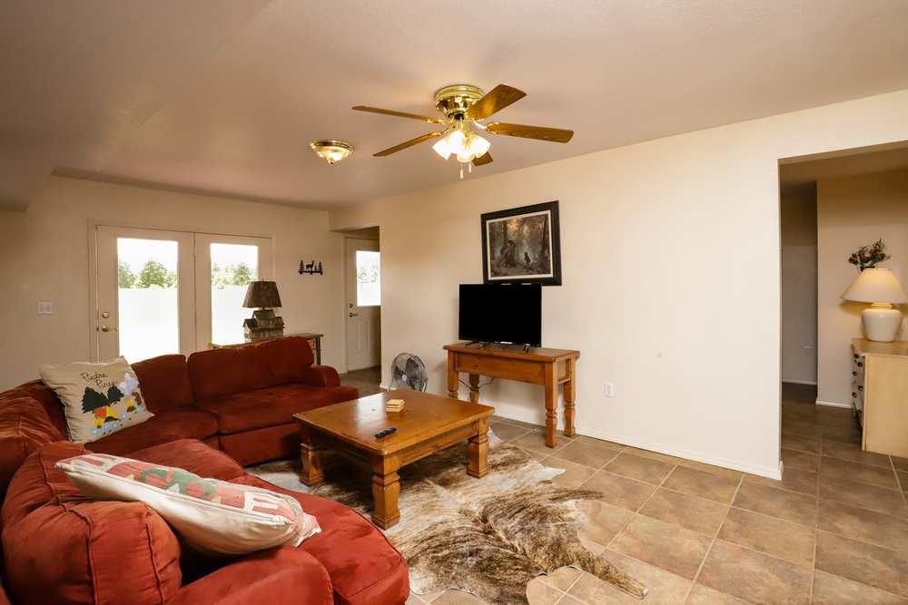 Lower-level living room with a red sectional, TV and French doors to the meadow