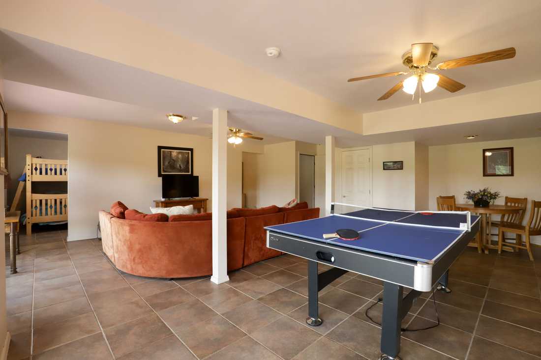 Lower-level game room with ping pong table, sectional and bunk room beyond