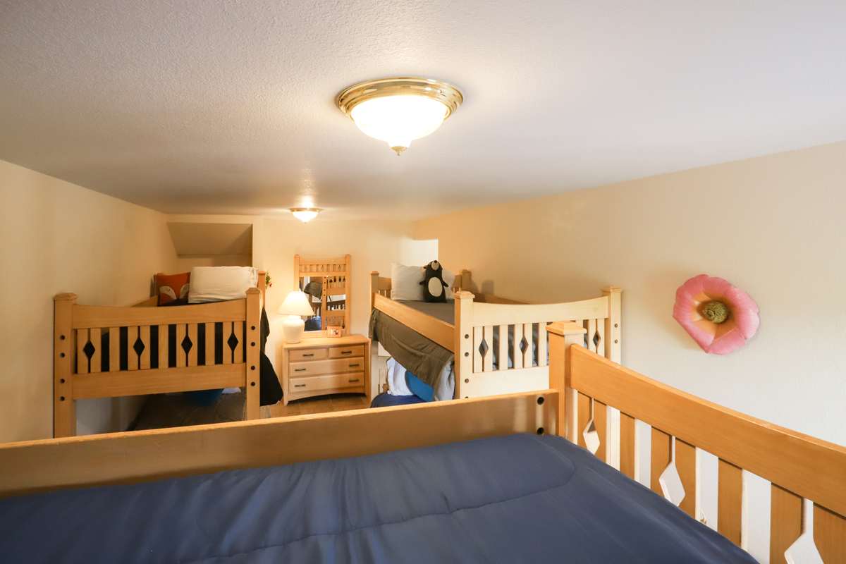 Bunk room seen from a top bunk with a dresser and second bunk set