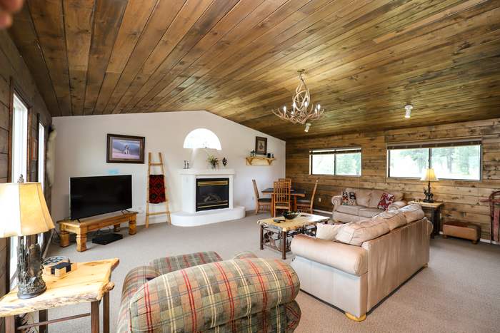 Second living room with a kiva fireplace, leather sofas and a wood-plank vaulted ceiling