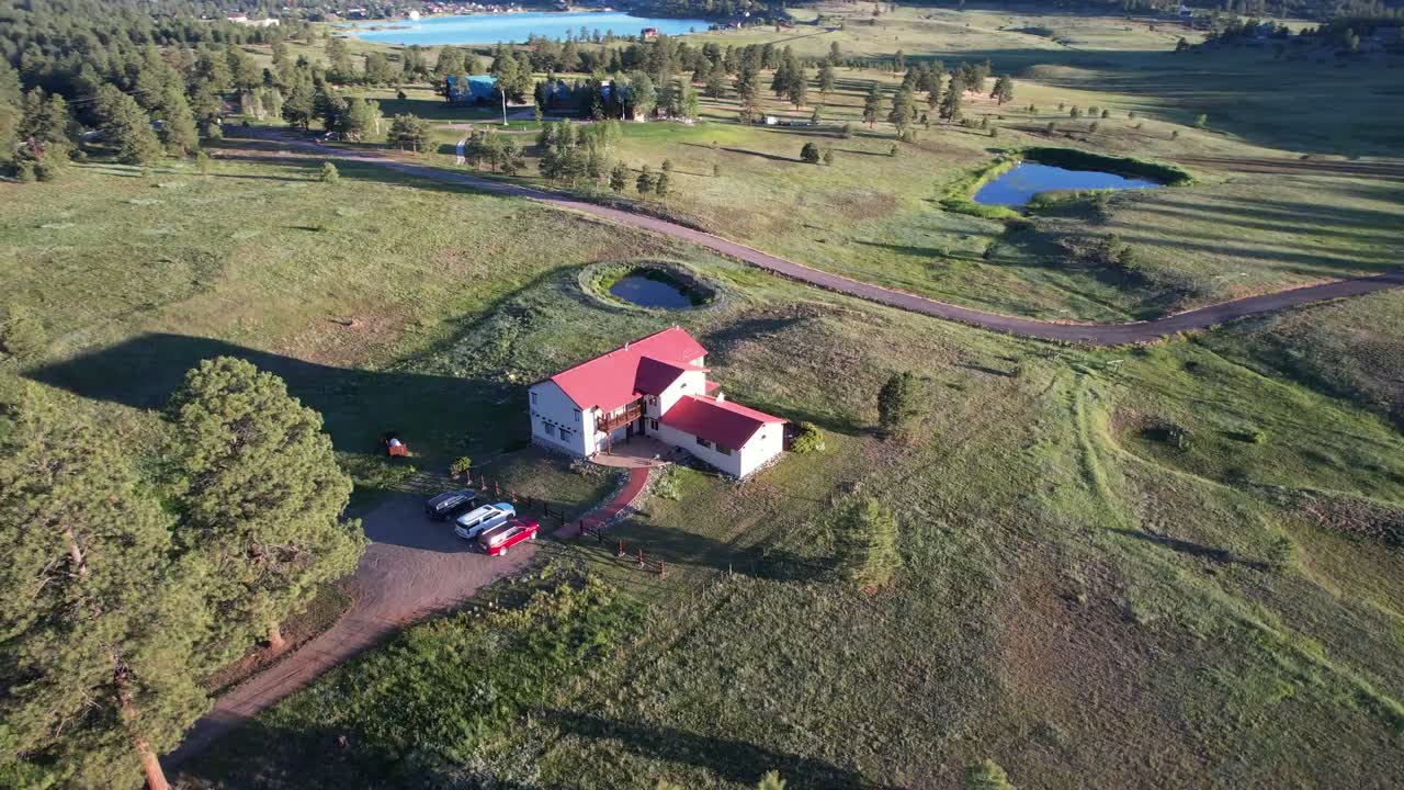Aerial view of Piedra Pines Lodge, its red roof among the pines and meadows near Pagosa Springs